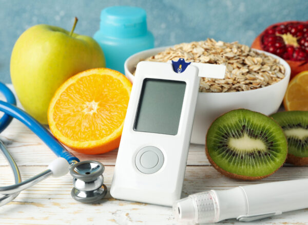 Blood glucose meter and diabetic food on wooden table