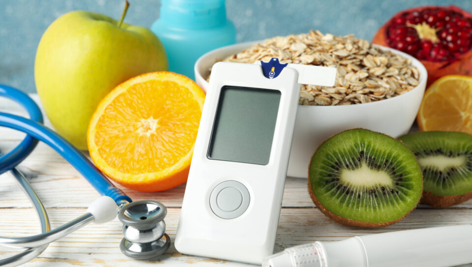 Blood glucose meter and diabetic food on wooden table