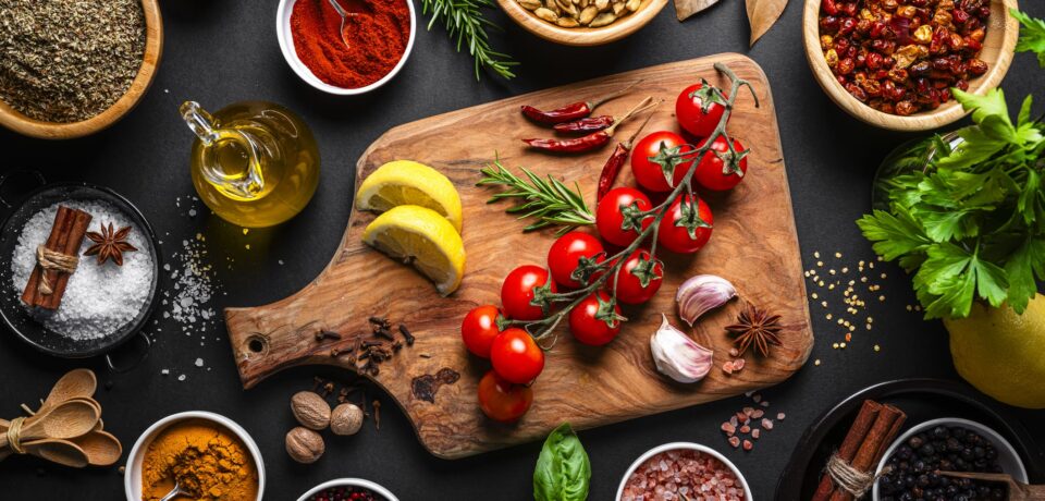 Culinary backgrounds: Group of spices, herbs and cooking ingredients shot from above on black background. Flat lay border or copy space