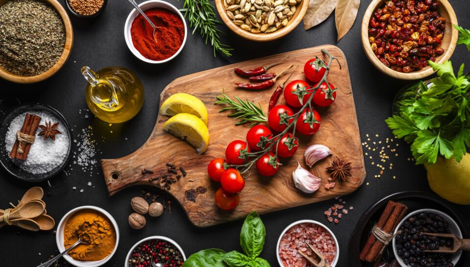 Culinary backgrounds: Group of spices, herbs and cooking ingredients shot from above on black background. Flat lay border or copy space